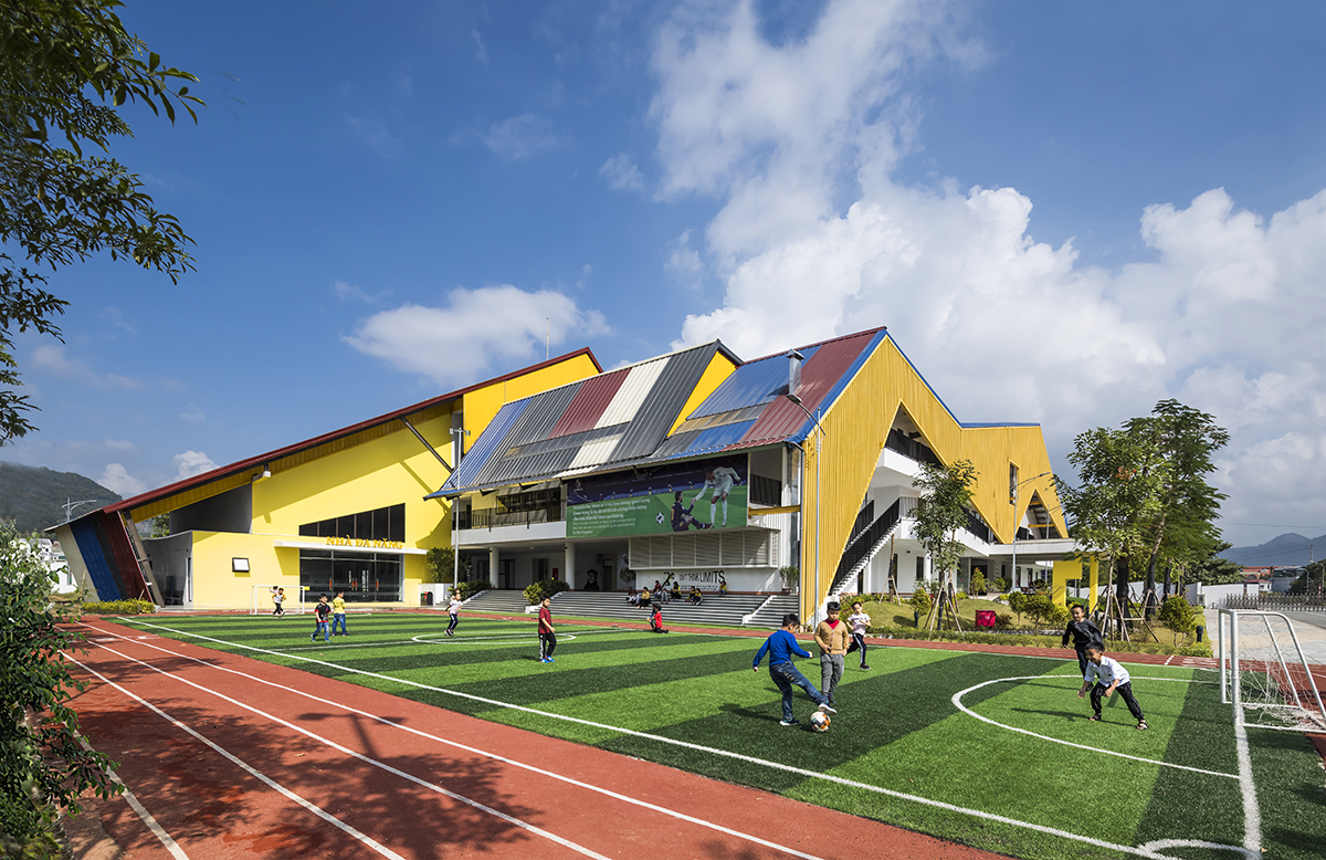 Học sinh chơi đá bóng trên sân cỏ nhân tạo trong khuôn viên trường