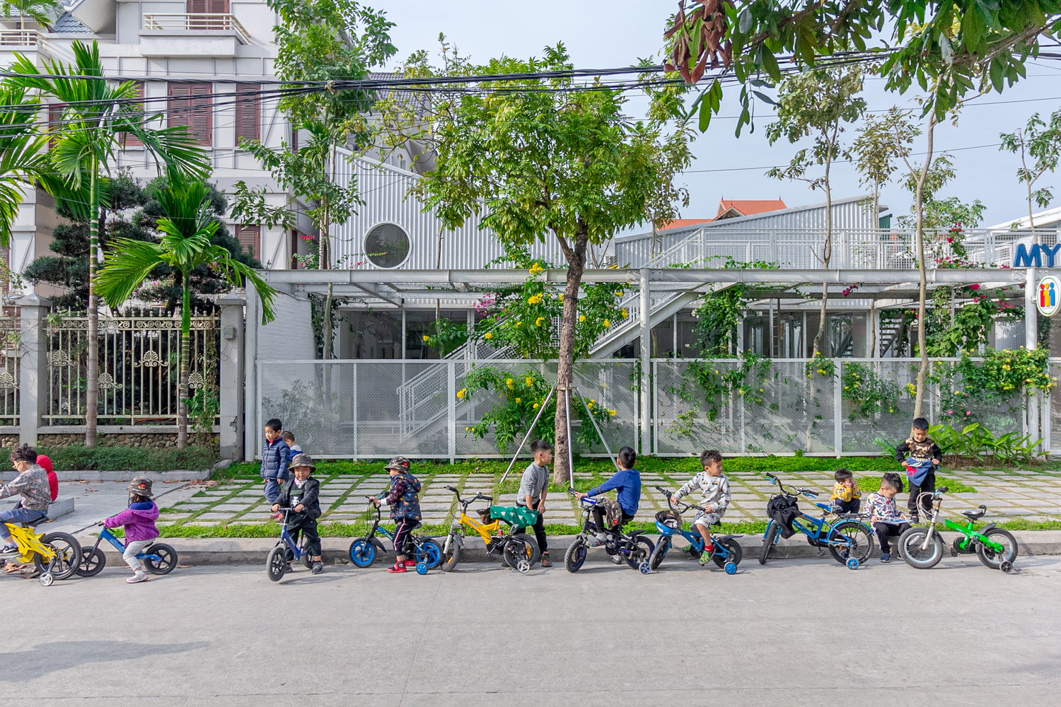Trẻ em đi xe đạp trước cổng trường mầm non