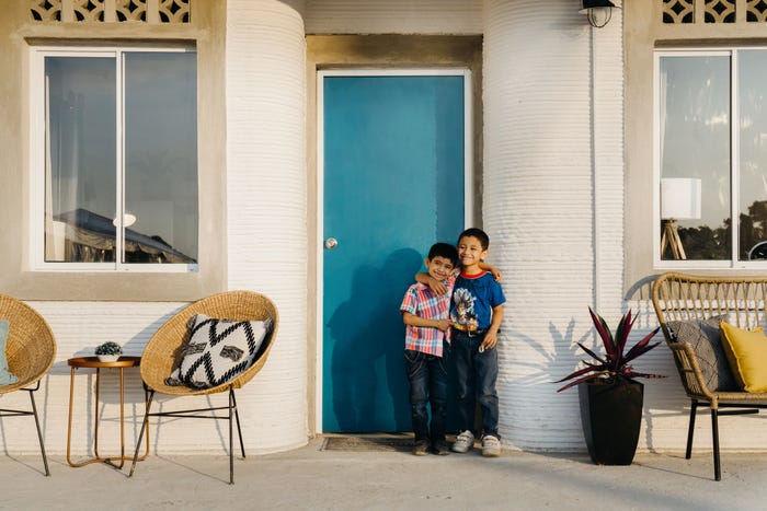 hai đứa trẻ đang ôm nhau trước cửa ngôi nhà in 3d