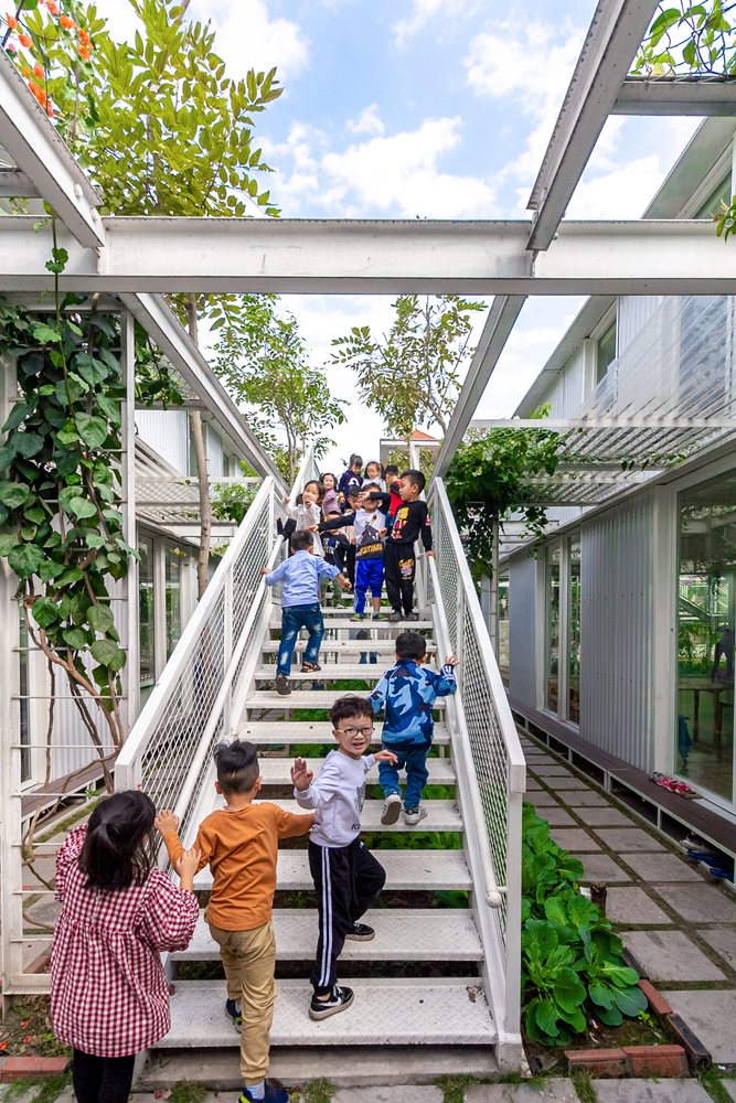 Trẻ em nô đùa trên cầu thang lớp học giữa vườn cây